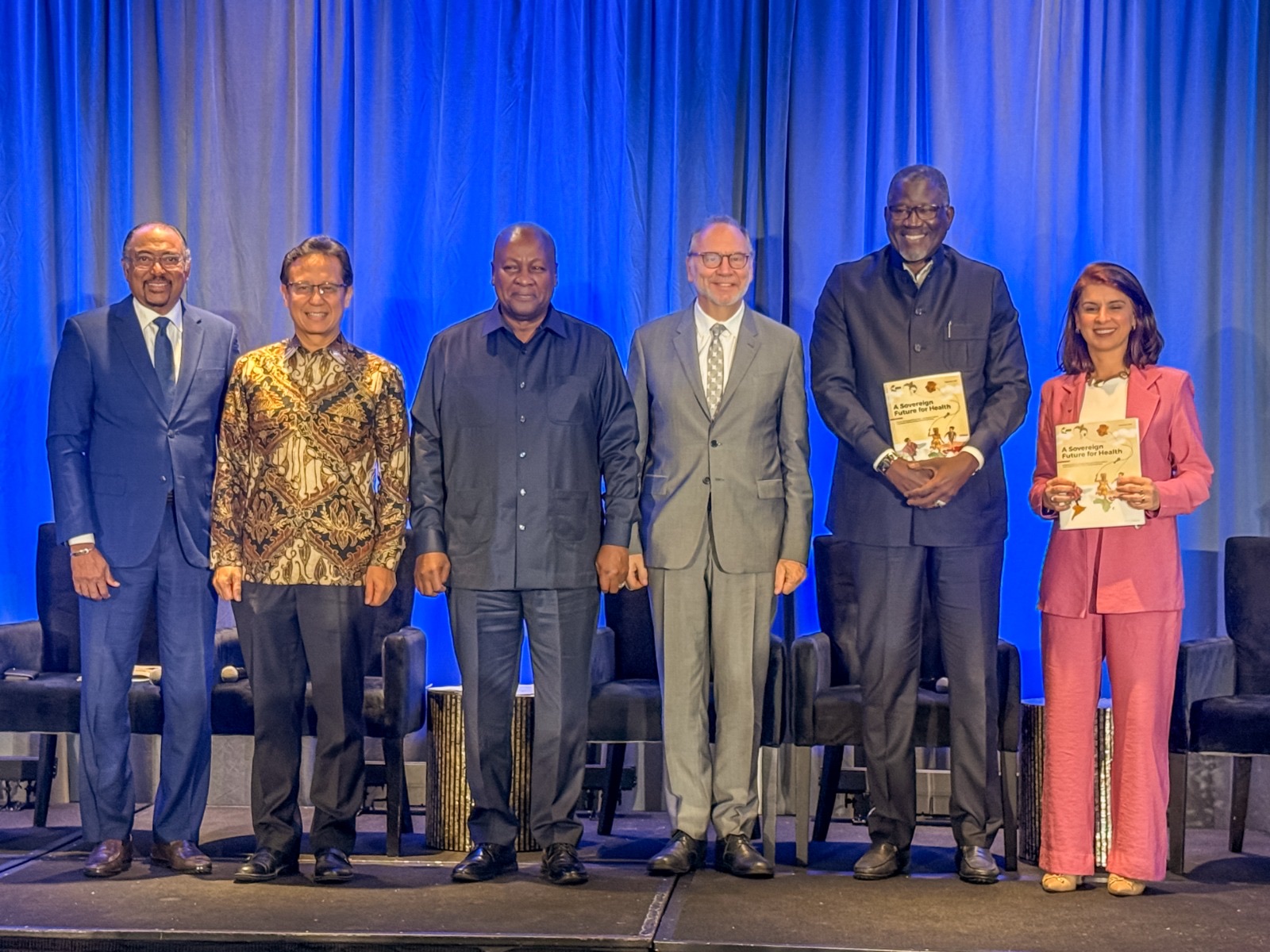 Panel members on stage at the Accra Reset Full Circle convening during UNGA 81, holding the report A Sovereign Future for Health